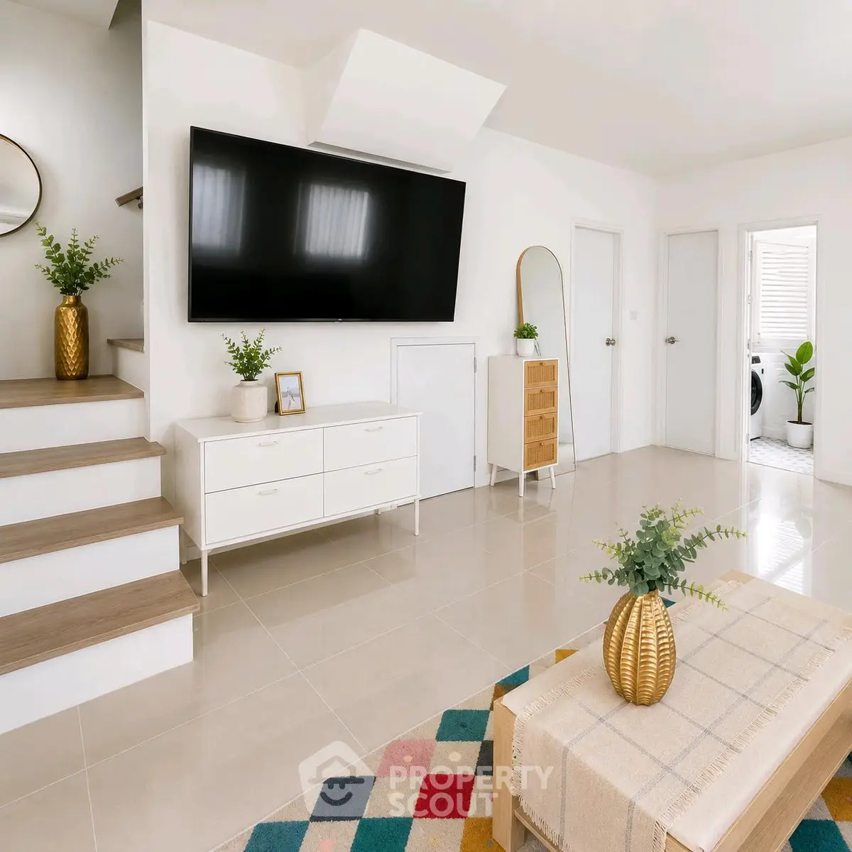 Modern living room with large TV, stylish decor, and natural light