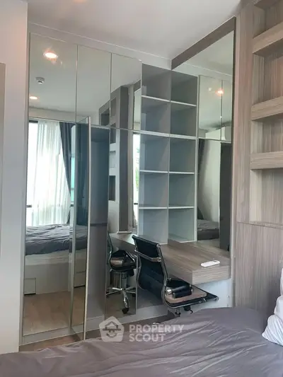 Modern bedroom with mirrored wardrobe and built-in study desk, featuring sleek design and natural light.