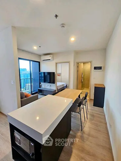 Modern open-plan living room with kitchen island and city view balcony in stylish apartment.