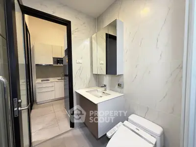 Modern bathroom with sleek fixtures and view into contemporary kitchen