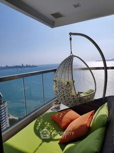 Stunning balcony with ocean view and cozy seating in a high-rise apartment.