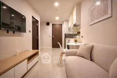 Modern living room with open kitchen, sleek furniture, and wall-mounted TV in a cozy apartment.