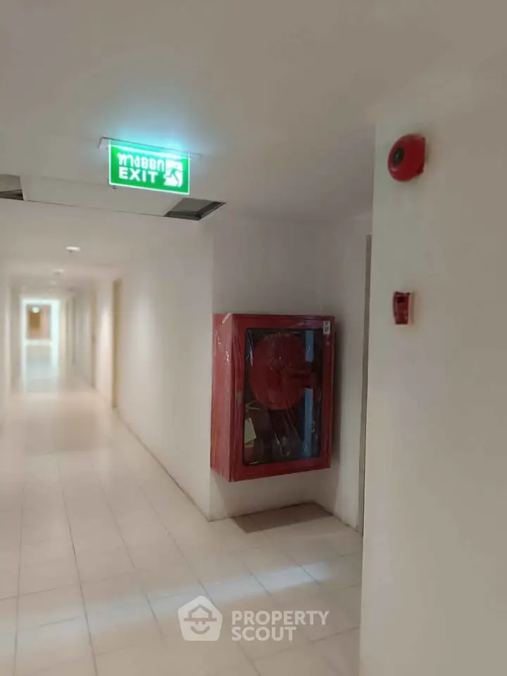 Modern building hallway with emergency exit sign and fire safety equipment