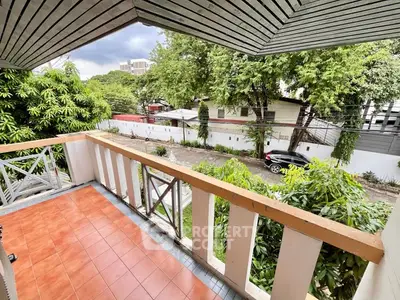 Charming balcony with scenic view of lush greenery and quiet street, perfect for relaxation.