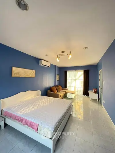 Spacious bedroom with blue walls, large window, and modern lighting in a cozy apartment.
