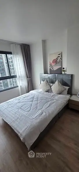 Modern bedroom with stylish decor and large window offering city view