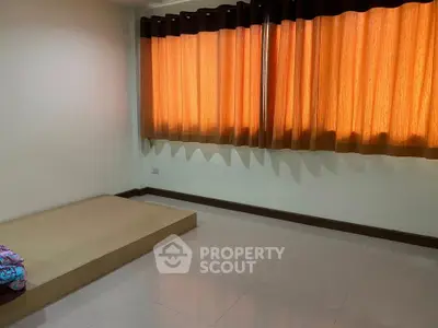 Minimalist bedroom with platform bed and orange curtains, ideal for cozy living.