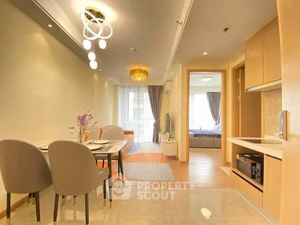Modern open-plan living and dining area with elegant lighting and cozy bedroom view.