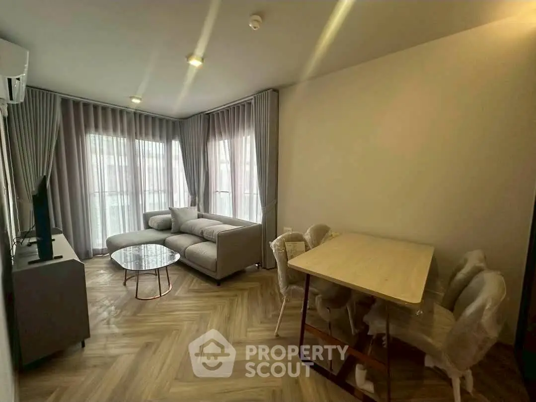 Modern living room with elegant decor and natural light, featuring a cozy sofa and dining area.