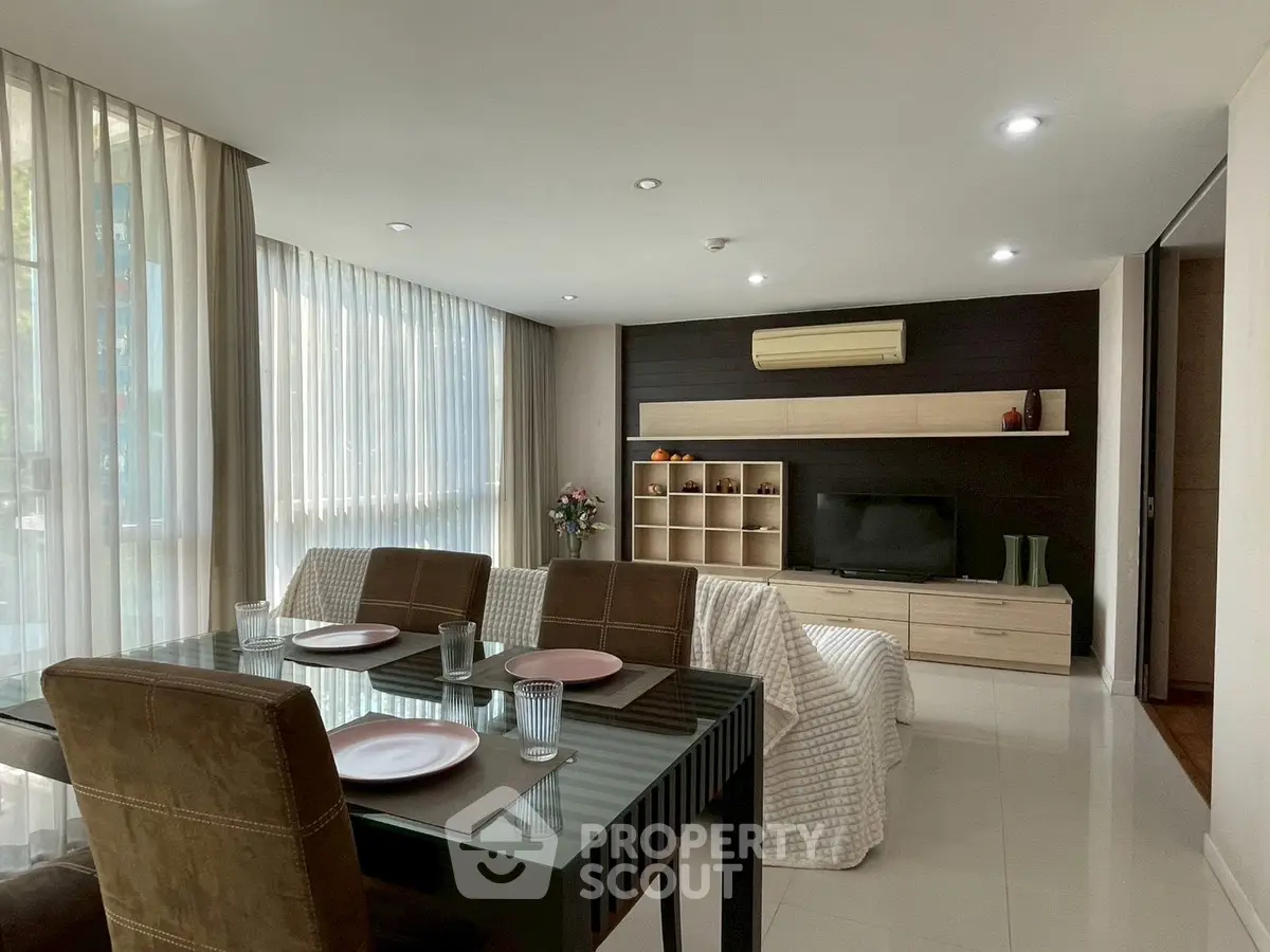 Modern living room with dining area, sleek furniture, and large windows for natural light.