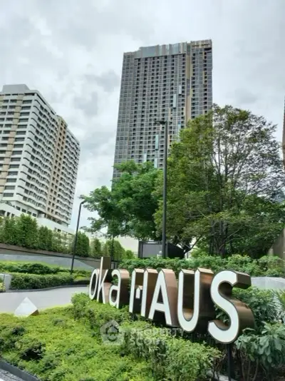 Modern high-rise building with lush landscaping and prominent signage in urban setting.