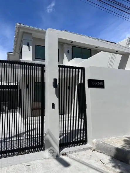 Modern two-story house with sleek gate and minimalist design in a sunny neighborhood.
