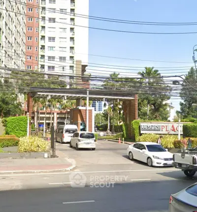 Modern condominium entrance with lush greenery and secure gated access.