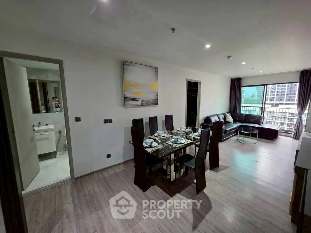 Modern open-plan living and dining area with city view and sleek furnishings.