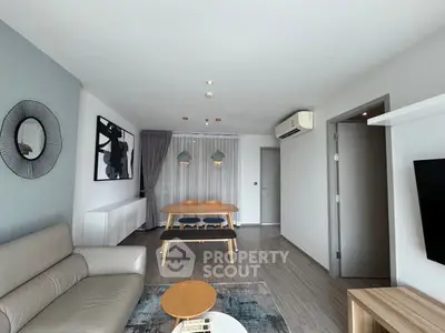 Modern living room with stylish decor and open dining area, featuring sleek furniture and contemporary design.