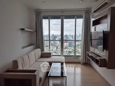 Modern living room with city view, featuring sleek furniture and large windows for natural light.