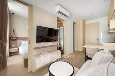 Modern apartment interior with open living room and bedroom, featuring sleek furniture and neutral tones.