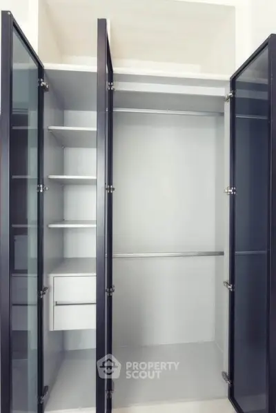 Spacious modern closet with glass doors and built-in shelves, perfect for organized storage.
