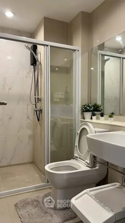 Modern bathroom with glass shower, sleek fixtures, and elegant tile design.