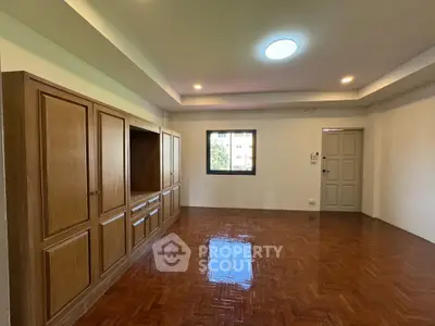 Spacious living room with wooden flooring and built-in cabinets, perfect for modern living.