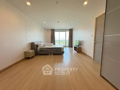 Spacious bedroom with modern decor and large window offering natural light.