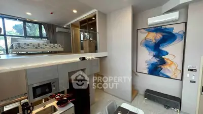 Modern loft apartment with stylish kitchen and mezzanine bedroom, featuring contemporary art and ample natural light.