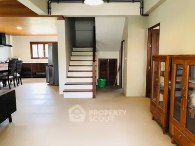 Spacious open-plan living area with modern staircase and elegant wooden furniture.