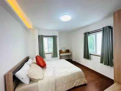 Cozy bedroom with natural light, wooden flooring, and modern furnishings in a serene setting.