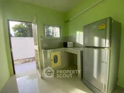 Charming compact kitchen with modern fridge and outdoor access, perfect for cozy living.