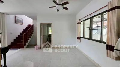 Spacious living room with ceiling fan and staircase in modern home