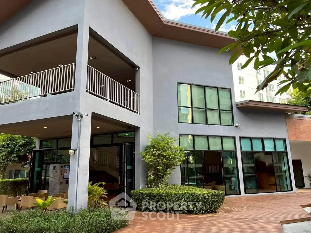 Modern two-story building with large windows and lush greenery