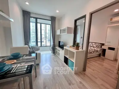 Modern open-plan living room with dining area and bedroom view in a stylish apartment.