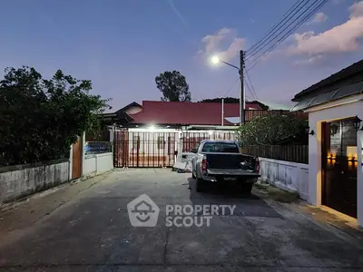 Charming suburban home with gated driveway and parked truck at dusk, showcasing a serene neighborhood ambiance.