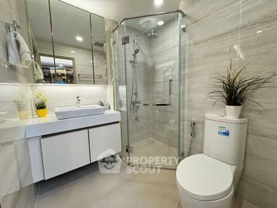 Modern bathroom with glass shower, sleek vanity, and elegant tile design.