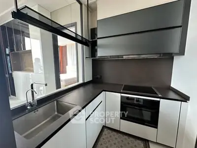 Modern kitchen with sleek black and white design, featuring built-in oven and ample counter space.