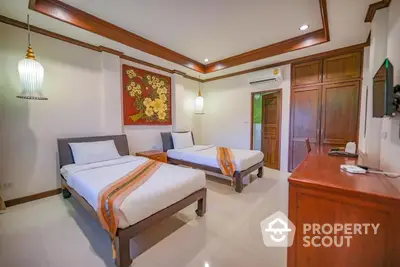 Elegant bedroom with two single beds adorned with traditional fabrics, polished wooden furniture, and a vibrant artwork, exuding a warm, cultural ambiance.