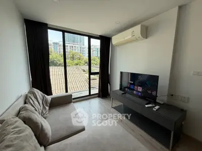 Modern living room with large window and city view, featuring cozy sofa and flat-screen TV.