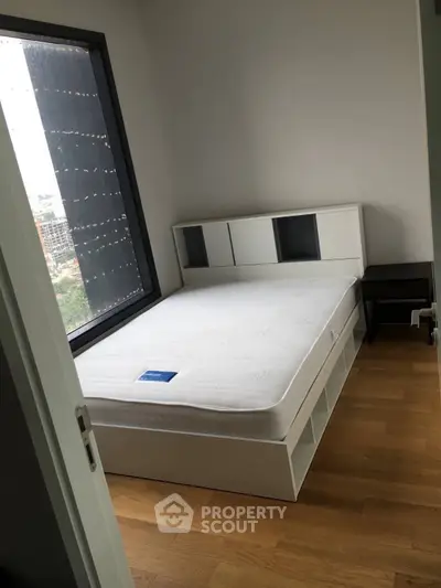 Modern bedroom with large window and sleek storage bed in urban apartment