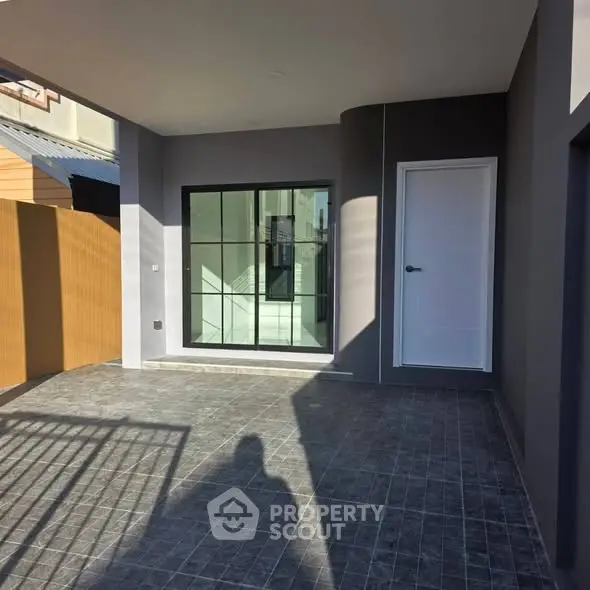 Modern home entrance with sleek design and spacious tiled patio area.