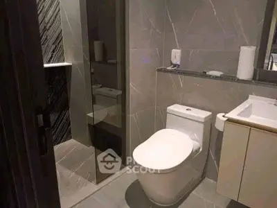 Modern bathroom with sleek design and elegant fixtures, featuring a spacious shower area and contemporary toilet.
