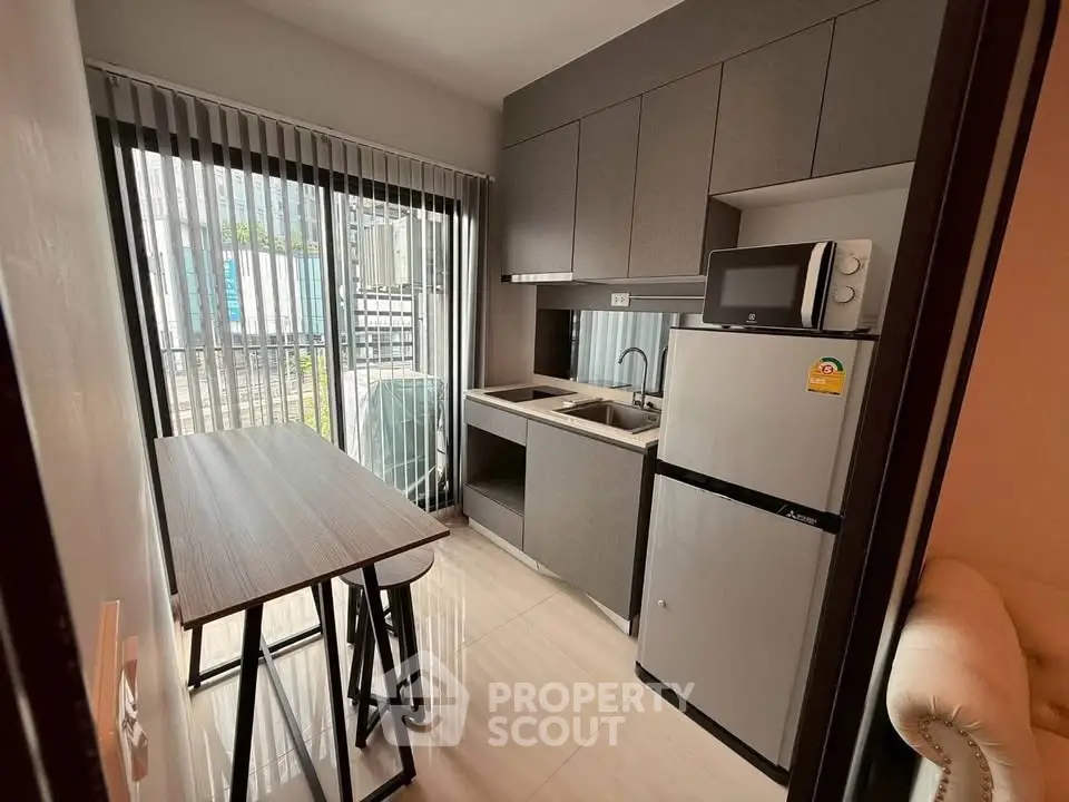 Modern compact kitchen with sleek cabinetry and stainless steel appliances in a cozy apartment.