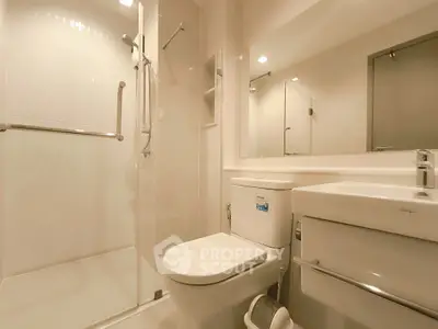 Modern bathroom with glass shower and sleek fixtures in contemporary apartment.