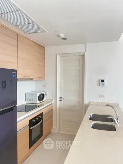 Modern kitchen with sleek appliances and wooden cabinetry in a stylish apartment.