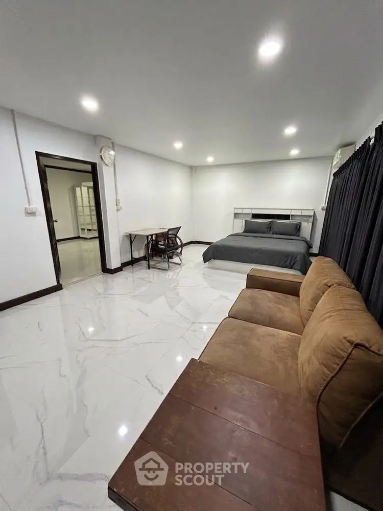 Spacious modern bedroom with cozy seating and elegant marble flooring