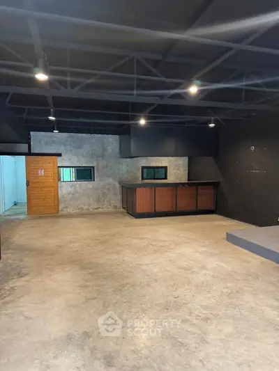 Spacious industrial-style interior with concrete floors and exposed ceiling beams, ideal for creative workspace.