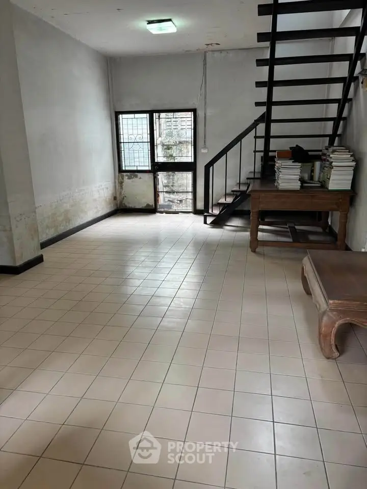 Spacious interior with tiled flooring and staircase, ideal for creative renovation.