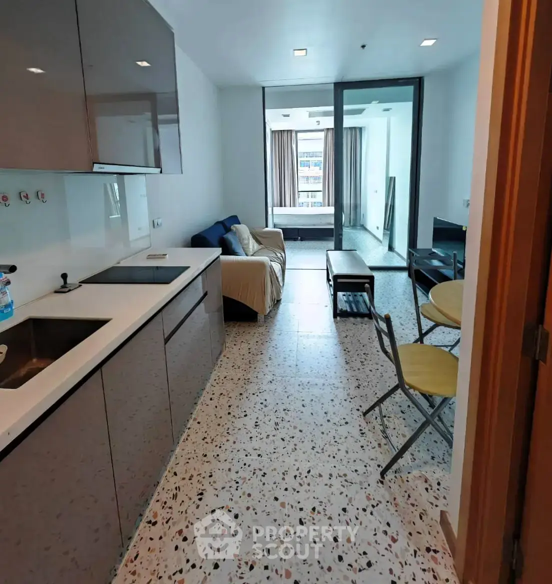 Modern open-layout kitchen and living room with terrazzo flooring and sleek cabinetry.