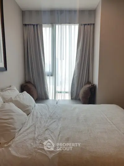 Cozy bedroom with large window and elegant curtains, perfect for relaxation.