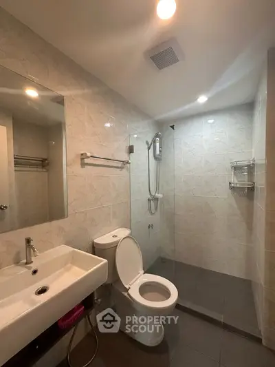 Modern bathroom with sleek fixtures and glass shower enclosure in a contemporary apartment.