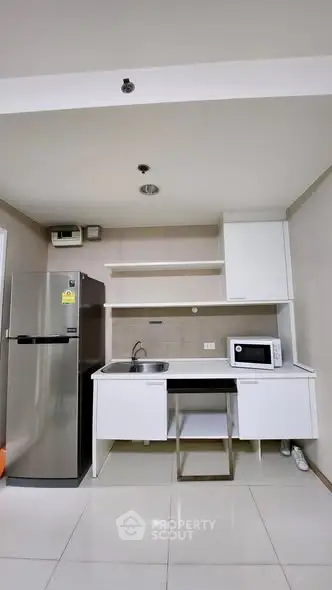 Modern kitchen with sleek white cabinets and stainless steel appliances in a compact layout.